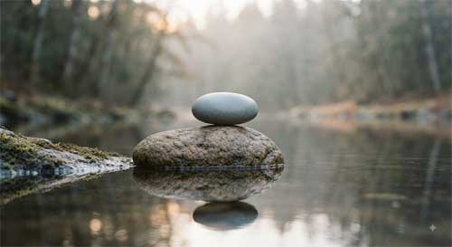 Piedras equilibradas junto a agua quieta simbolizando mente unificada y presencia clara