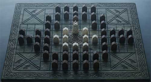 Tablero de Hnefatafl con piezas de madera oscura y clara dispuestas en formación de diamante alrededor del rey