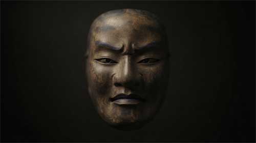 Máscara tradicional japonesa beshimi con boca cerrada y expresión serena pero firme, iluminación tenue lateral resaltando textura madera, atmósfera de silencio protector