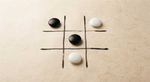 Tablero minimalista de Tres en Raya dibujado con tinta negra sobre papel de arroz, con piedras de Go como fichas