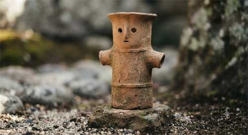 Figura Haniwa de terracota con expresión serena y formas cilíndricas