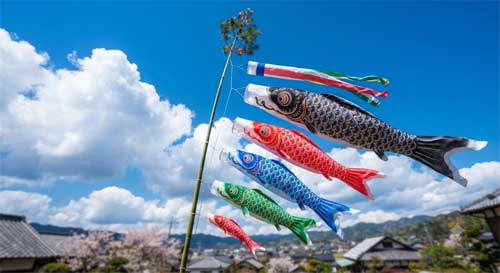 Varias carpas de viento de colores ondeando bajo un cielo azul con nubes