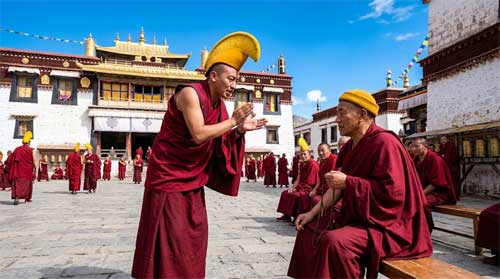 Monjes debatiendo en el patio de un monasterio Gelug con sombreros amarillos característicos