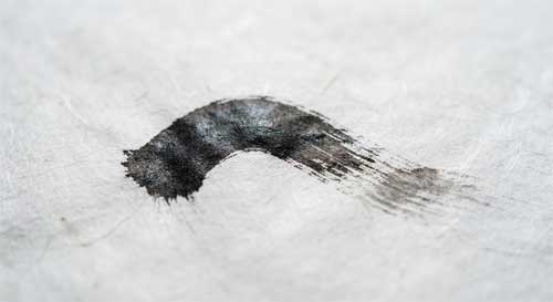 Trazo único y poderoso de tinta negra sobre papel de arroz blanco, mostrando la textura del pincel y la espontaneidad del gesto zen