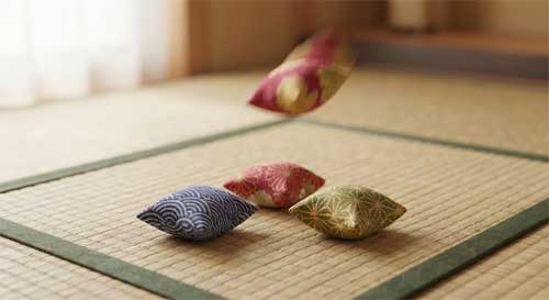 Saquitos de tela tradicionales japoneses (otedama) en colores vibrantes dispuestos sobre una superficie de madera tatami