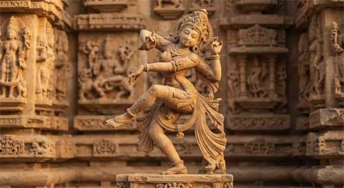 Escultura antigua de una danzarina india en pose dinámica, con detalles ornamentales finos y fondo de templo