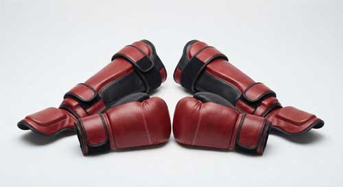 Guantes de sparring acolchados y protectores de espinillas dispuestos ordenadamente, estilo minimalista
