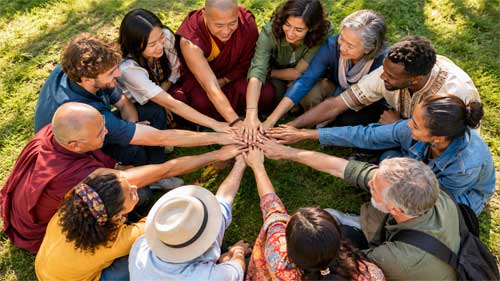 Grupo diverso de personas de diferentes edades y culturas sentadas en círculo en un entorno natural, con manos entrelazadas simbolizando unidad y activismo pacífico bajo la luz del sol