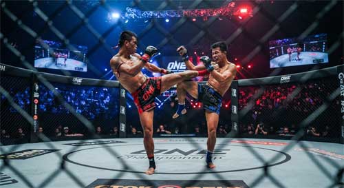 Vista dinámica del octágono de ONE Championship con luces dramáticas, mostrando la intensidad de un combate de Muay Thai o MMA con atletas en plena acción