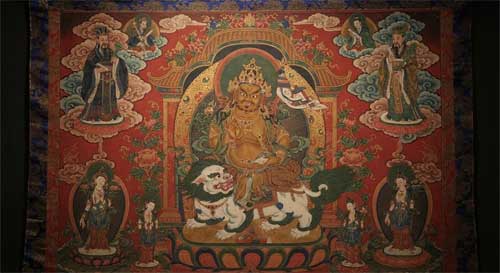 Thangka tibetana estilo Ming temprano, deidad central Vaisravana sobre fondo rojo, esquinas superiores con figuras de funcionarios taoístas chinos barbudos flotando en nubes